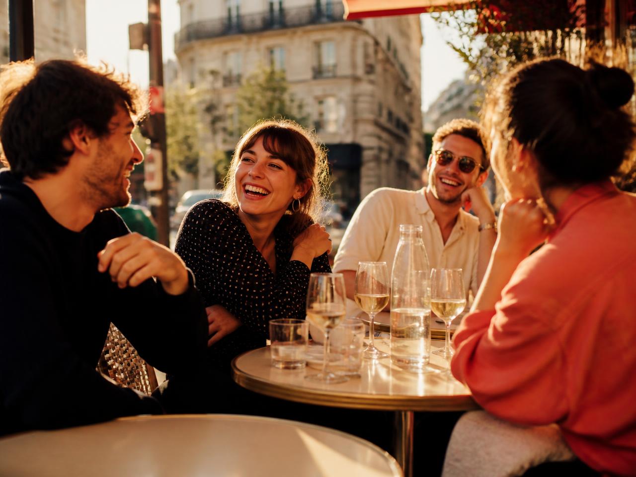 Un groupe d'amis qui rit autour d'une table en terrasse